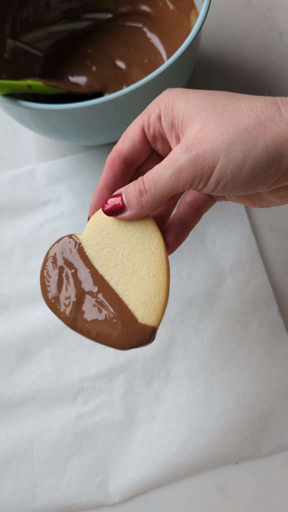 Dipping heart shaped sugar cookies into tempered chocolate